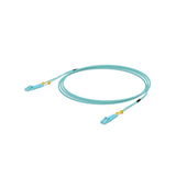Cable de fibra óptica azul claro OM3 con conectores LC y protectores amarillos enrollado sobre fondo blanco