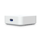 Perspectiva tres cuartos del gateway cloud blanco Ubiquiti mostrando la base gris y pantalla OLED frontal