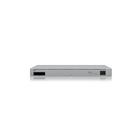 Parte trasera del switch de red mostrando ventilación, logotipo Ubiquiti y conectores de alimentación sobre fondo blanco