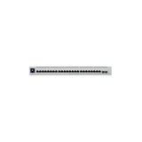 Primer plano frontal del conmutador mostrando 24 puertos Ethernet negros, ranuras SFP+ y pantalla LCD azul