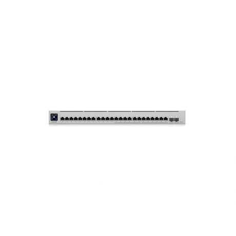 Primer plano frontal del conmutador mostrando 24 puertos Ethernet negros, ranuras SFP+ y pantalla LCD azul