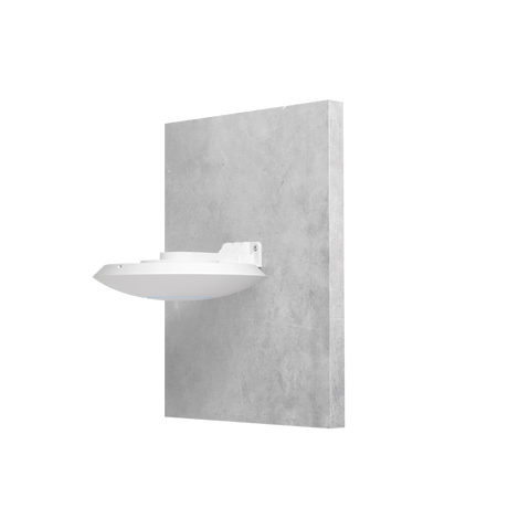 Soporte blanco UniFi montado en pared de concreto gris sosteniendo un punto de acceso discreto